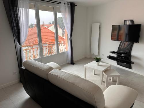 un salon avec un canapé et une grande fenêtre dans l'établissement Envies D’Ailleurs Centre Ville, à Saint-Brévin-les-Pins