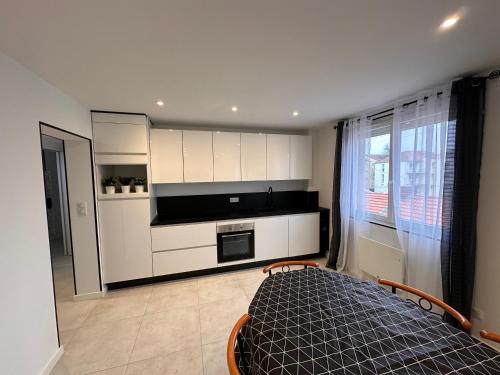 une cuisine avec des armoires blanches et un lit dans une chambre dans l'établissement Envies D’Ailleurs Centre Ville, à Saint-Brévin-les-Pins