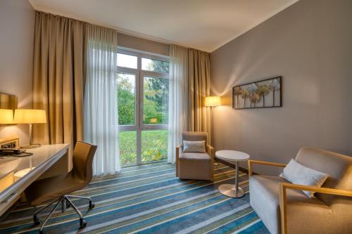 a hotel room with a desk and chair and a window at Mercure Düsseldorf Kaarst in Kaarst