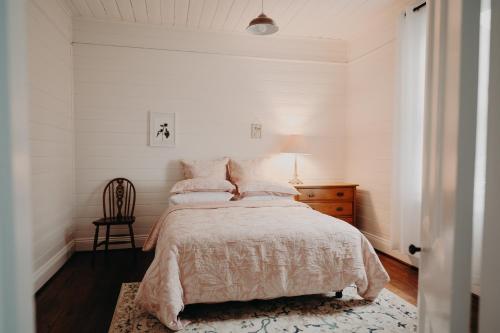 a white bedroom with a bed and a chair at Balnagown in Albany
