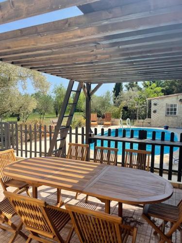 une table et des chaises en bois sous un parasol en bois dans l'établissement Mas Provençal de 120m2 en Camargue, Avec Piscine et Parking inclus, Idéal pour des vacances, à Arles