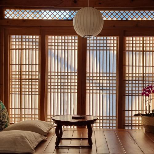 une chambre avec une table devant les fenêtres dans l'établissement Dalbbit hyang, à Jeonju