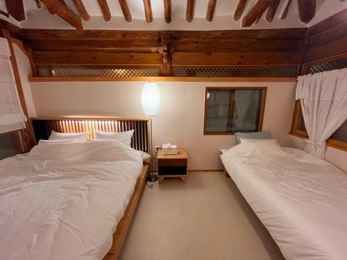 two twin beds in a room with wooden ceilings at Dalbbit hyang in Jeonju