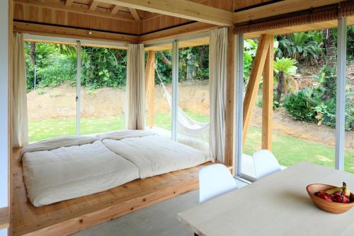 a bedroom with a bed in a room with windows at SHINMINKA Villa UTTABARU - Vacation STAY 92209 in Amami