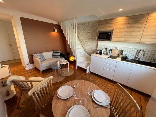 a kitchen and a living room with a table and chairs at L'Horizon - Duplex face à la Mer tout confort in Saint-Aubin-sur-Mer
