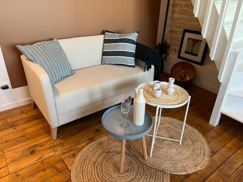 a living room with a couch and two tables at L'Horizon - Duplex face à la Mer tout confort in Saint-Aubin-sur-Mer