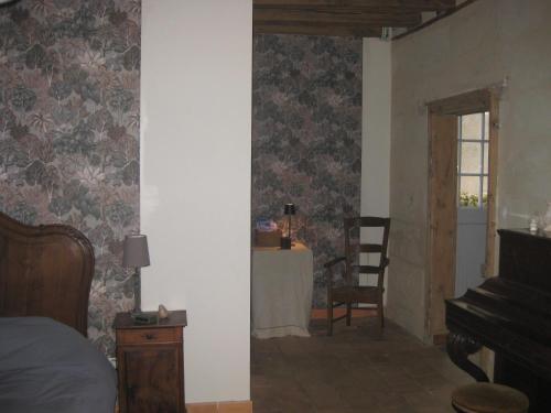 une chambre avec un lit, une table et un piano dans l'établissement Le Logis de Cléré, à Cléré-les-Pins