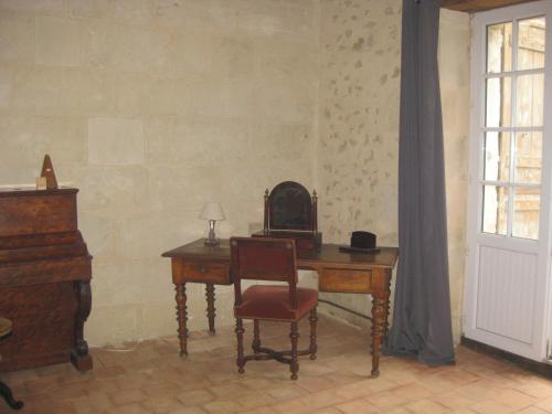 Cette chambre comprend un bureau avec une chaise et un piano. dans l'établissement Le Logis de Cléré, à Cléré-les-Pins