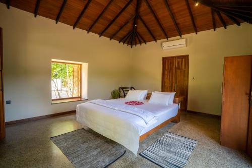 una camera da letto con un grande letto bianco e una finestra di Omkara Rekawa a Tangalle