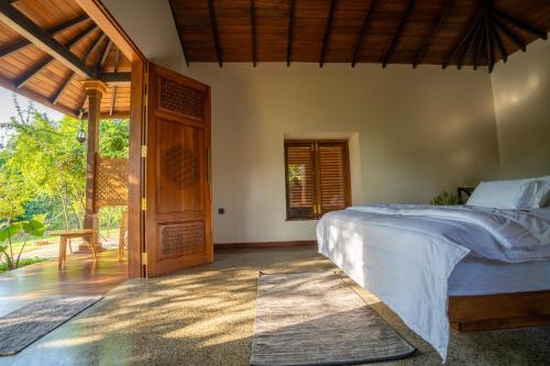 1 dormitorio con 1 cama y puerta de madera en Omkara Rekawa, en Tangalle