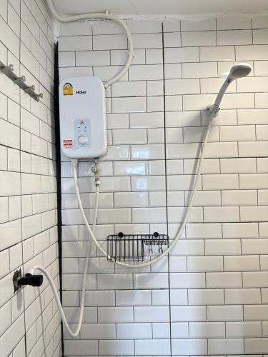 a white tiled bathroom with a shower head at Chubby 9 Room 7 in Bangkok