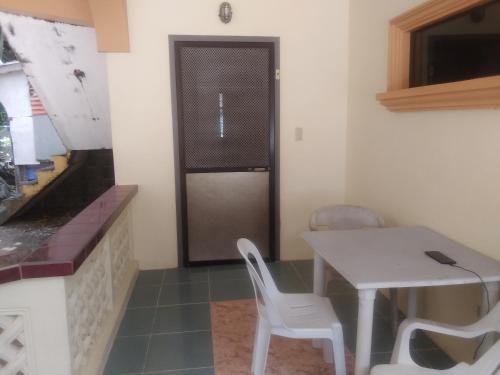 - une petite cuisine avec une table et des chaises blanches dans l'établissement Kaye En Em Apartelle, à Puerto Galera
