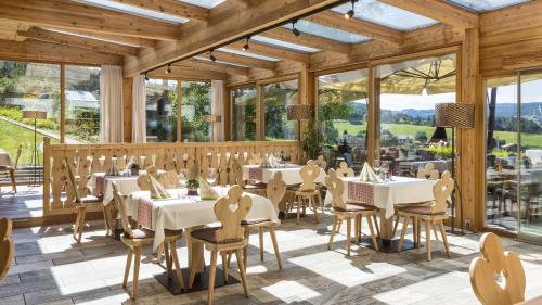 ein Restaurant mit weißen Tischen, Stühlen und Fenstern in der Unterkunft Dolmites Nature Hotel Vigilerhof in Seis am Schlern