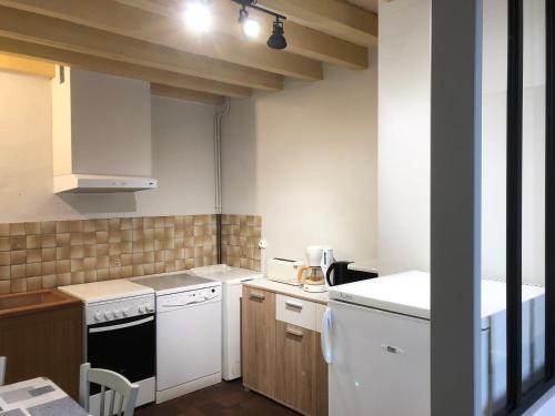 una pequeña cocina con electrodomésticos blancos y armarios de madera. en La Renardie, en La Ferté-Imbault