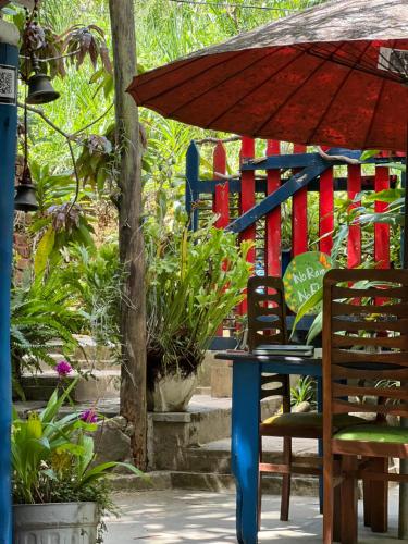 a table and chairs with an umbrella and some plants at Moksha eco villa Ella in Ella