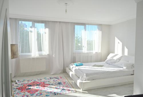 a white bedroom with two beds and a rug at Ahmet teacher's villa, 6 minutes from the airport in Arnavutköy