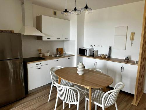 een keuken met een tafel en stoelen en een koelkast bij Bel appartement vue mer - Mafat'appart in La Possession