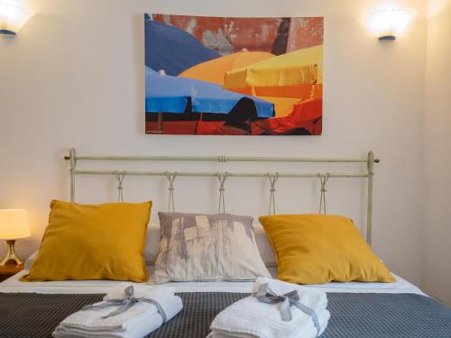 - une chambre avec un lit doté d'oreillers jaunes et d'un tableau dans l'établissement Mainetta Sea View Apartment with AC, à Vernazza