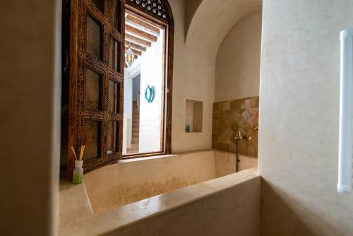 un ampio bagno con vasca e finestra di Riad Cologne & Spa a Marrakech