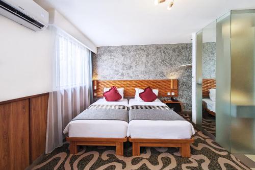 a bedroom with a large bed with red pillows at THE 1O1 Bandung Dago in Bandung