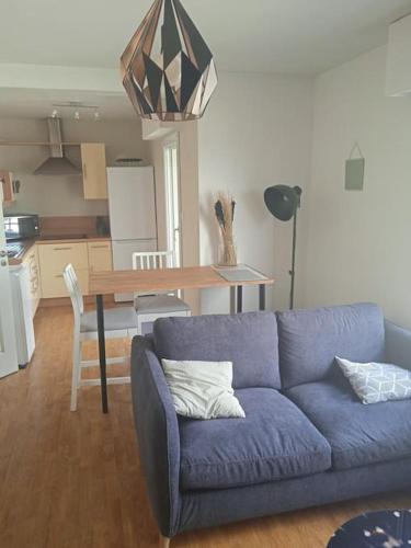 un salon avec un canapé bleu et une table dans l'établissement Cocoon - Appartement Centre Ville Concarneau, à Concarneau