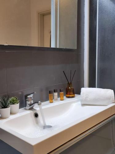 une salle de bain avec un lavabo blanc et un miroir dans l'établissement Cocoon - Appartement Centre Ville Concarneau, à Concarneau