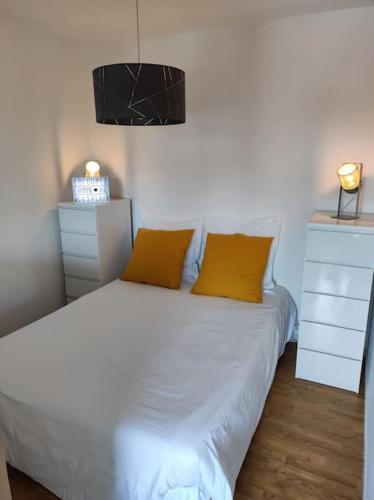 - une chambre avec un lit blanc et 2 oreillers jaunes dans l'établissement Cocoon - Appartement Centre Ville Concarneau, à Concarneau