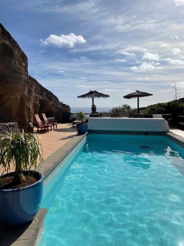 una piscina con agua azul y sombrillas en Castillo Lanzarote Villa Bailey - Luxury Villa - Pet friendly with heated Pool, en La Asomada