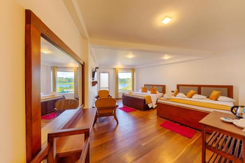 a room with two beds and a table and chairs at Eden Hill Hotel in Nuwara Eliya