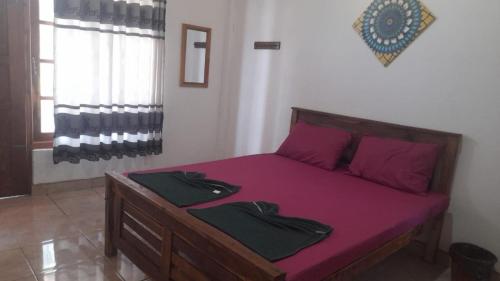um quarto com uma cama com lençóis roxos e almofadas roxas em Suriya Villa em Kandy