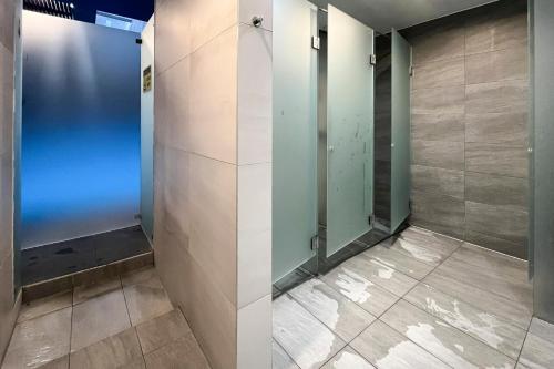 Łazienka z przeszklonymi drzwiami i podłogą wyłożoną kafelkami w obiekcie Modern Wellness Studio w Budapeszcie