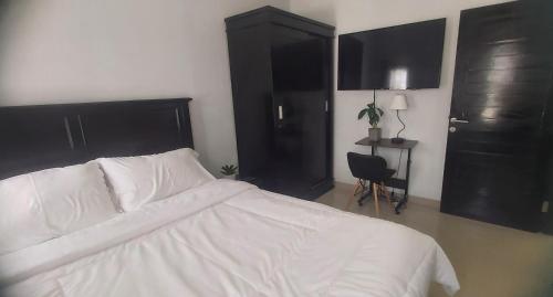 - une chambre avec un lit blanc et des armoires noires dans l'établissement Chandra's guest house, à Pesanggaran