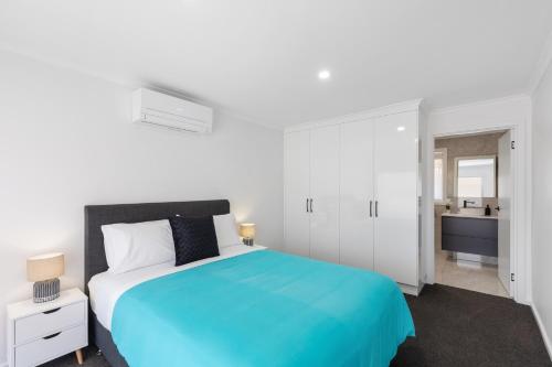 a white bedroom with a blue bed and a bathroom at Heinlen on North Terrace in Mount Gambier