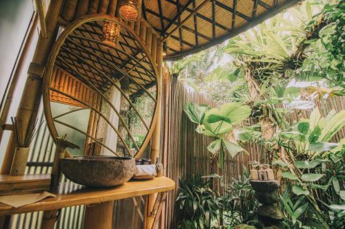 a room with a wall with plants and a bowl at Hideout Eco Bamboo House Bali in Selat