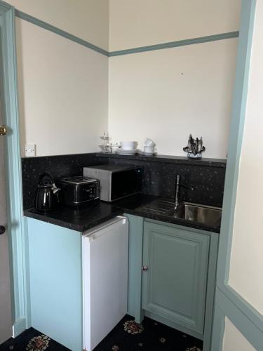 a small kitchen with a sink and a microwave at Ivybank Villa in Rothesay