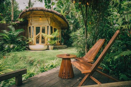 a wooden deck with a bench and a table and a tree house at Hideout Eco Bamboo House Bali in Selat