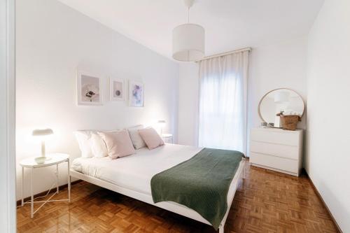 a white bedroom with a bed and a mirror at Pink Flat by Quokka 360 - close to the Italian border in Chiasso