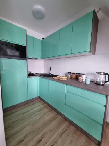 a kitchen with blue cabinets and a wooden floor at Dom na Ubocy in Groń