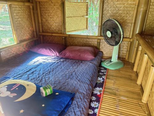 a small bedroom with a bed and a fan at Khaosok August Freedom Camp in Khao Sok