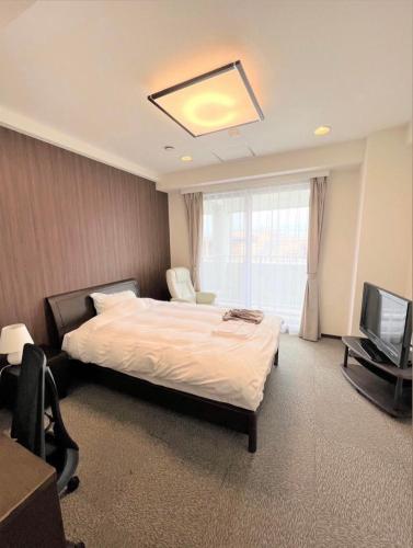 een hotelkamer met een bed en een televisie bij ホテル辰巳俱楽部 