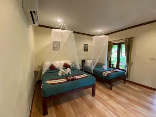 Khao Sok River & Jungle Bungalow في خاو سوك: غرفة معيشة بها سريرين وأريكة