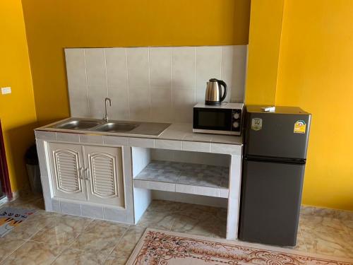 una pequeña cocina con fregadero y microondas en Fullmoon Jomtien Guest house, en Jomtien Beach