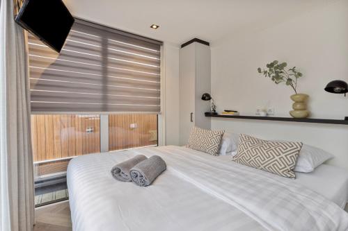 a bedroom with a large white bed with a window at Luxurious waterloft near beach and centre by Weltevreden Experience in Zeewolde