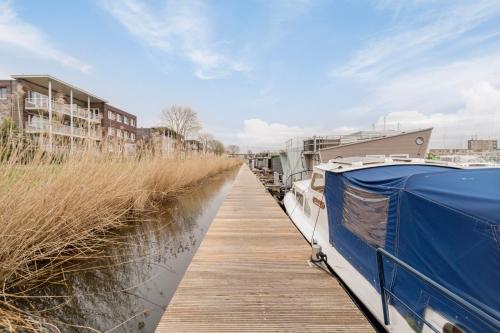 a boat is docked next to a dock at Luxurious waterloft near beach and centre by Weltevreden Experience in Zeewolde