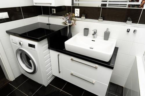 a white bathroom with a sink and a washing machine at BNB New Beautiful Apartment in the Center of Ostrava with option Garage Parking in Moravská Ostrava