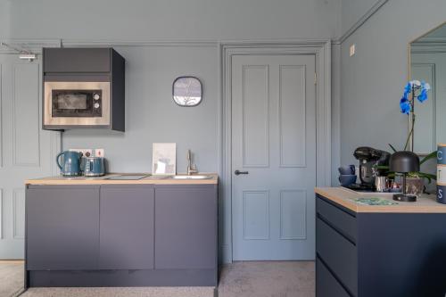 a kitchen with white cabinets and a white door at Bluebell Studio Glasgow Airport in Paisley