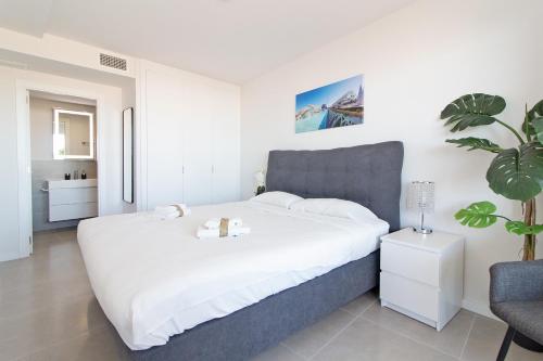een slaapkamer met een groot wit bed en een stoel bij Global Properties, Apartamento para 6 personas con terraza in Canet de Berenguer