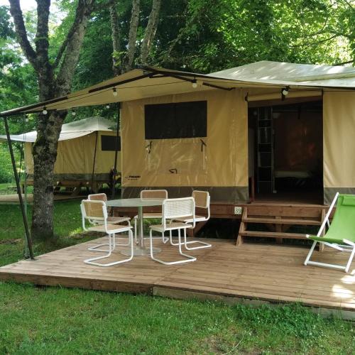 - une table et des chaises sur une terrasse en face d'une tente dans l'établissement Tentes canadienne - Camping des trois rivières, à Bassignac
