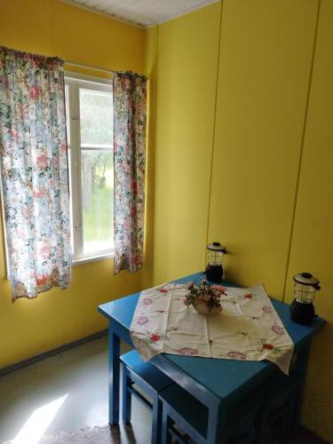une table bleue dans une pièce jaune avec fenêtre dans l'établissement Topsala MidIsland, à Houtskari