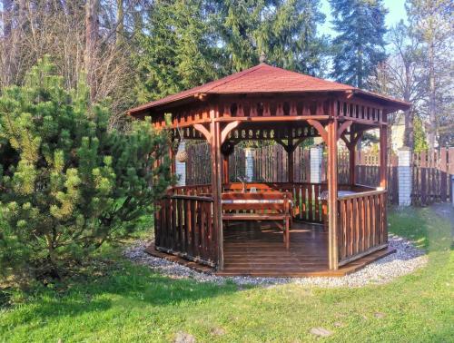 a wooden gazebo with a bench in a yard at APARTMÁN POHODA in Svatava